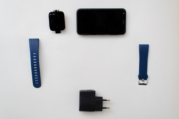 Layout of smart watch accessories.Smart watch, two silicon watchbands,smartphone and charger on white background.Space for text in centre.