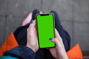 Woman wearing fashion clothes in dark blue and orange holding iPhone11 iPhone XR green screen, blue...