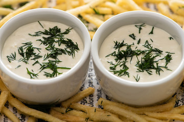 close up of garlic sauce with dill near crispy french fries