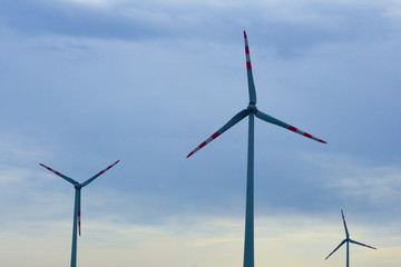 Modern windmills stand in a field against the sky