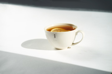 Cup of tea with lemon on white background.