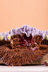Chocolate cupcakes on a wooden table with flowers from the cremama, with fruit jam inside.