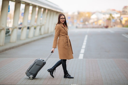 Full body side portrait of business woman walking with suitcase in terminal
