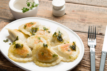 Fried dumplings with herbs on wood.