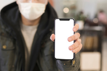 Front view of man with medical mask holding up phone