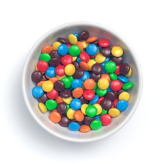 Colorful coated chocolate candies in white bowl isolated on white background