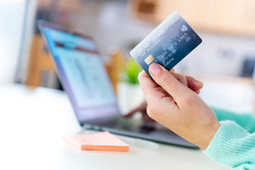 Close up of a grey colour credit card in a hand of a young caucasian modern female.