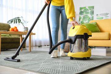 Young woman hoovering floor at home