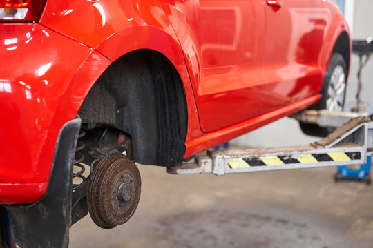 Rusty drum brakes, rear on red car. Change the old to new brake disc on car in a garage. Auto mechanic repairing