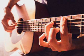 Young man's hands playing acoustic guitar, close up