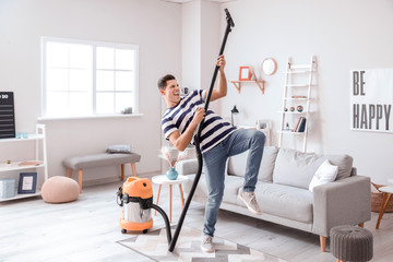 Young man having fun while cleaning floor at home