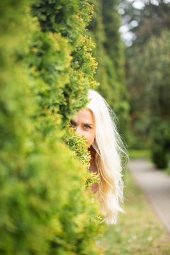 Blonde Woman With Long Hair On A Summer Day Hiding Behind The Bush