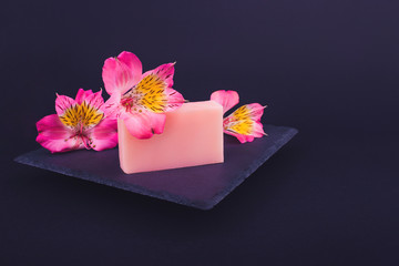 Fototapeta na wymiar Handmade soaps and flowers on black background. Skin care concept. Beauty. Natural Soap making. Soap bars closeup. 
