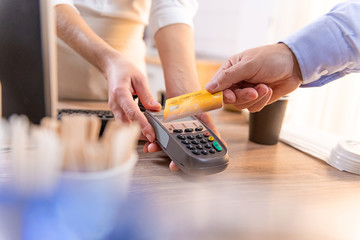 A man paying for coffee with a golden credit card in a coffee shop