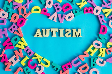 Multicolored letters in the shape of a heart and the word autism on a blue background. Autism Day. Autism spectrum disorder concept.