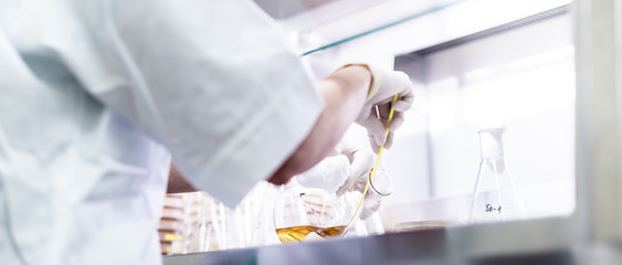Female scientist working with laminar flow at corona virus vaccine development laboratory research...