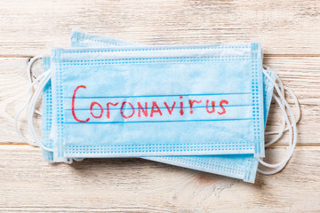 Close up of stack of medical masks with coronavirus word on wooden background. Wuhan virus. World...