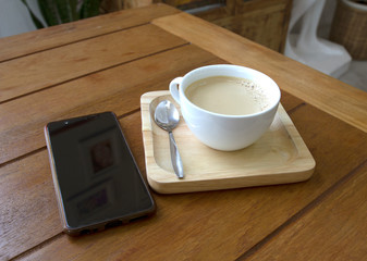 cup of hot coffee and mobile phone on a wooden table