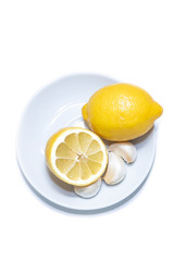Lemon and garlic on a white plate, backstage. White background and place for copy.