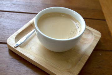 A cup of coffee in a white cup on wooden background