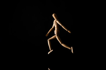 Wooden doll imitating running on black