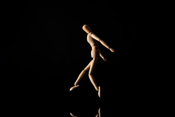 Fototapeta na wymiar Wooden doll imitating jumping on black