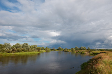 Obraz na płótnie Canvas cloudy clouds over the river in summer
