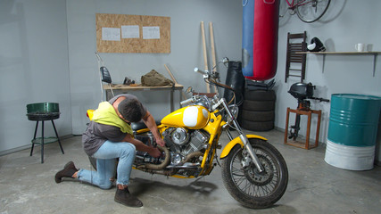 Fototapeta na wymiar Man can’t fix a motorcycle part in a garage