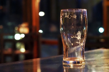 Empty beer glass on a table in a dark bar, pub - 331692855
