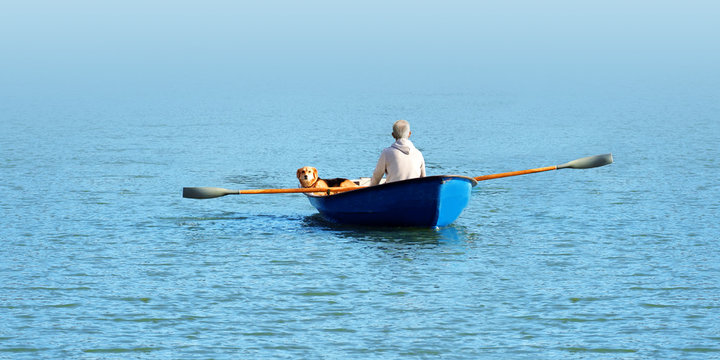 Elderly man and a dog swim in a boat in the water, panoramic view