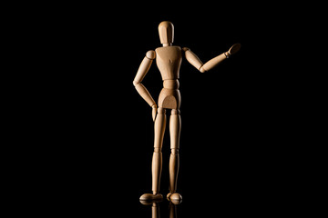 Wooden doll with hand on hip imitating pointing with hand on black background