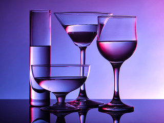 Different glass goblets on a and purple background. Beautiful still life