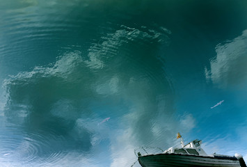 Reflection in the water of a ship and clouds