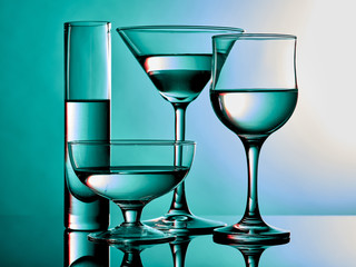 Different glass goblets on a turquoise background. Beautiful still life