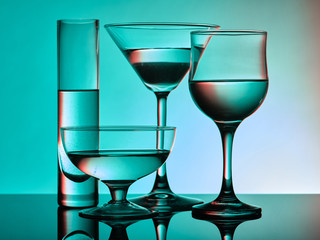 Different glass goblets on a turquoise background. Beautiful still life