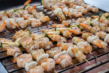 Outdoor picnic scene of seafood bbq with delicious shrimp on skews and prawn spits on a grill 
