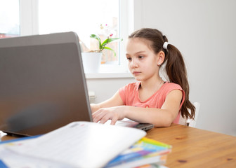 Caucasian preteen girl concentrated on her task with laptop. Concept of distance learning in isolation while coronavirus