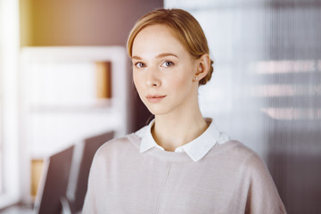 Friendly adult casual dressed business woman standing straight. Concept of a business headshot or portrait in office