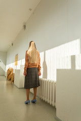 Blond girl standing in the white sunny hall