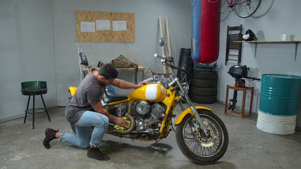 Fototapeta na wymiar Young man wipes a motorcycle with a rag in the garage