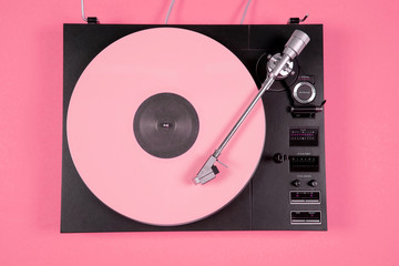 Colored vinyl record on a pink background with copy space.
