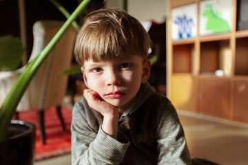 Ein vierjähriger Junge sitzt gelangweilt in seinem Zimmer am 18.03.2020. - obrazy, fototapety, plakaty