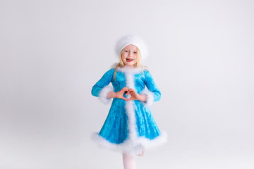 Little blonde girl in a christmas and new year Santa costume having fun and sending kisses on red background. Space for text. Dreams come true Merry Christmas