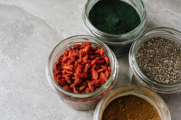 Selection of healthy nutritious superfoods for a healthy lifestyle. Dried goji berries, chia seeds, spirulina, carob in a close up view