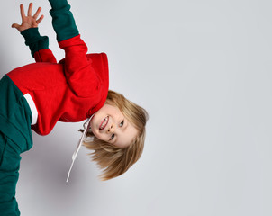 Portrait of happy smiling active frolic blond kid boy in dark gray and red hoodie and pants playing