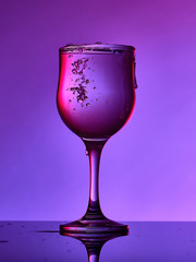 Different glass goblets on a and purple background. Beautiful still life