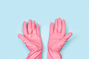 Manos con guantes de látex de color rosa sobre fondo celeste liso. Vista superior. Copy space. Concepto: Limpieza