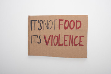 top view of cardboard sign with its not food its violence inscription on white background