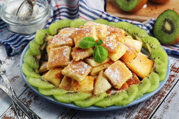 Austrian dessert Kaiserschmarrn served with sugar powder and kiwi fruit