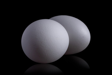 White organic chicken eggs isolated on a black background